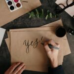 Artistic calligraphy session featuring the word 'yes!' with natural eucalyptus accents.