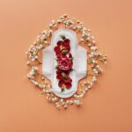 Artistic flatlay of a sanitary pad adorned with flowers on a peach background, symbolizing menstruation.